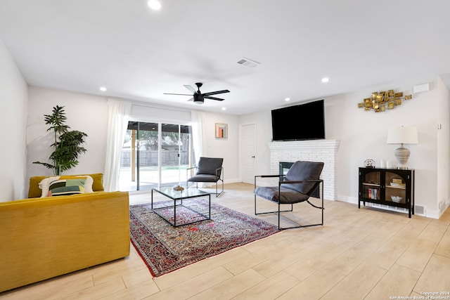 living room featuring a fireplace, light hardwood / wood-style floors, and ceiling fan