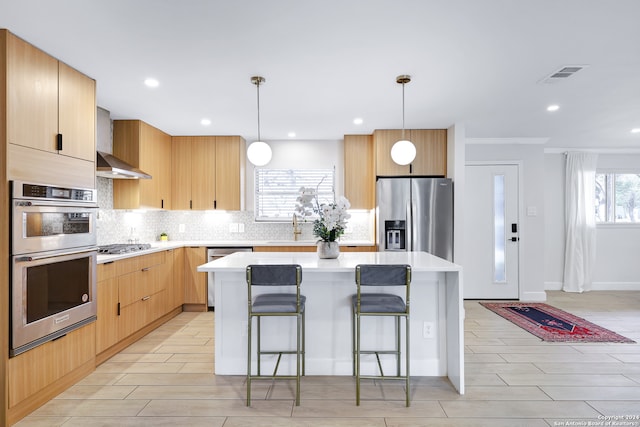 kitchen featuring hanging light fixtures, a kitchen bar, a kitchen island, and appliances with stainless steel finishes