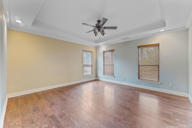 empty room with hardwood / wood-style flooring, ceiling fan, a raised ceiling, and crown molding