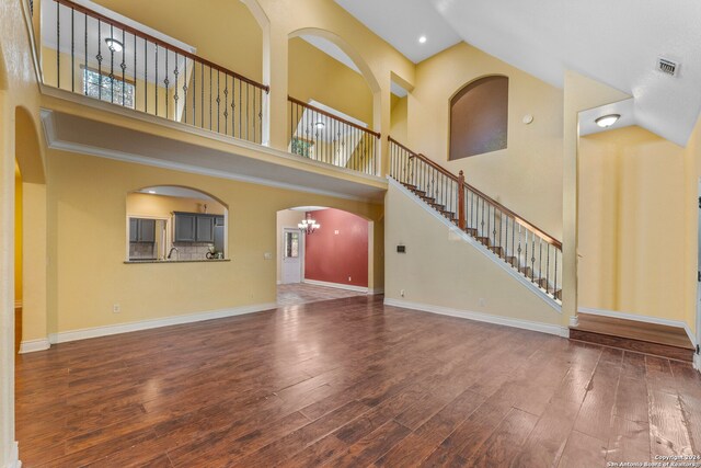 unfurnished living room featuring high vaulted ceiling, a notable chandelier, and dark hardwood / wood-style floors