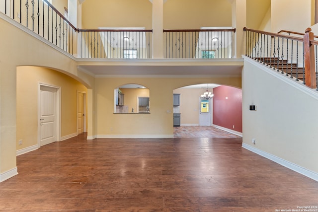 unfurnished living room featuring hardwood / wood-style floors, a chandelier, and a high ceiling