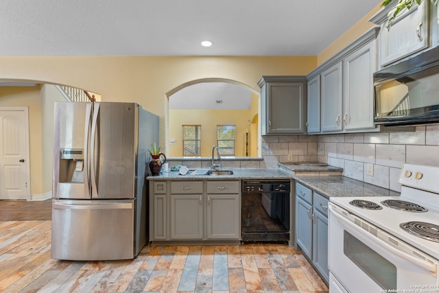 kitchen featuring black appliances, light wood-type flooring, backsplash, gray cabinets, and sink