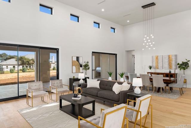 living room featuring light wood-type flooring and a towering ceiling