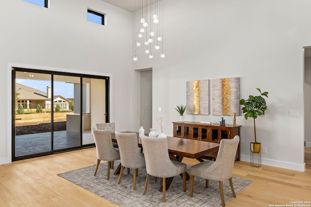 dining space with a towering ceiling and light hardwood / wood-style flooring