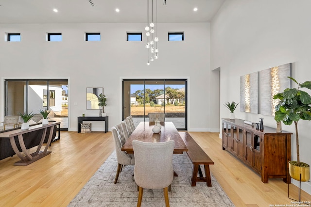 dining area with light hardwood / wood-style flooring and a towering ceiling