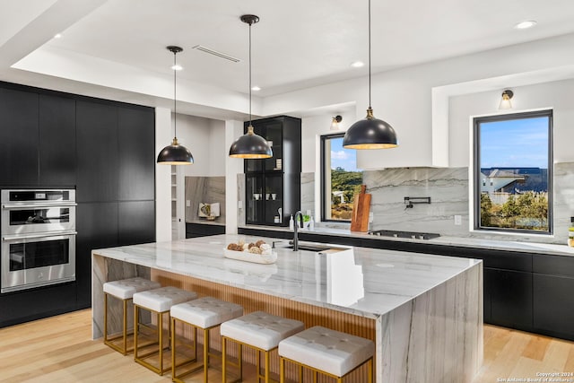 kitchen with pendant lighting, a spacious island, sink, light hardwood / wood-style floors, and stainless steel appliances