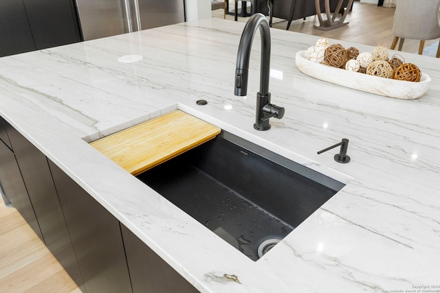 room details with light stone countertops, sink, and hardwood / wood-style flooring