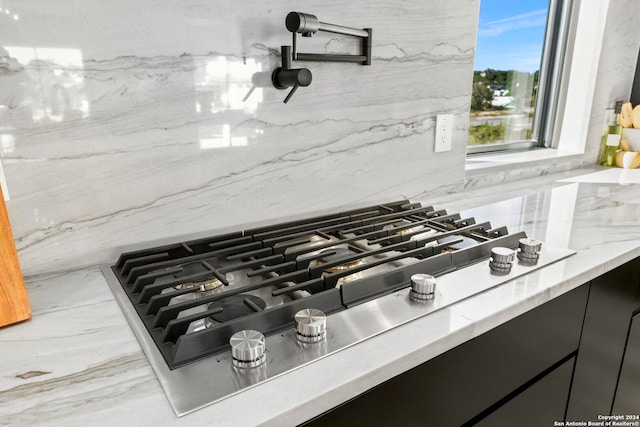 details with decorative backsplash and stainless steel gas stovetop