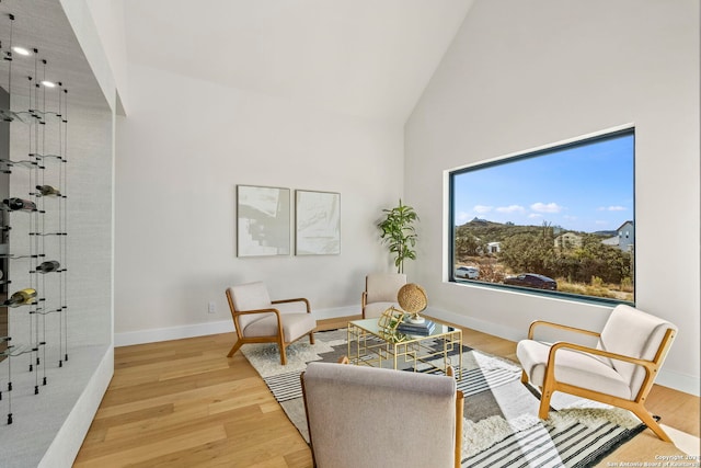 sitting room with wood-type flooring and high vaulted ceiling