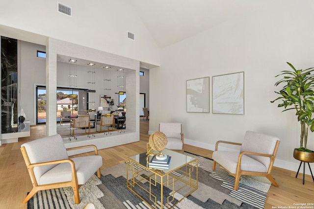 sitting room with light wood-type flooring and high vaulted ceiling