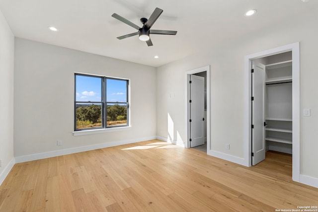 unfurnished bedroom featuring ceiling fan, light hardwood / wood-style floors, a spacious closet, and a closet