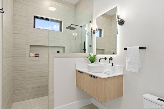 bathroom featuring vanity, toilet, and a tile shower