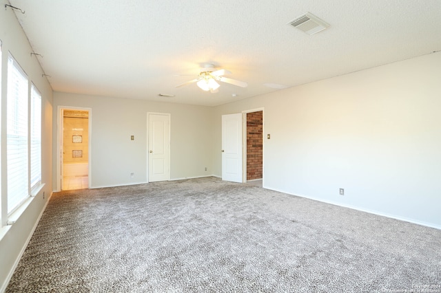 unfurnished room featuring a textured ceiling, carpet floors, ceiling fan, and a healthy amount of sunlight