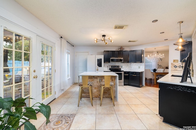 kitchen featuring decorative backsplash, stainless steel appliances, decorative light fixtures, a chandelier, and a center island