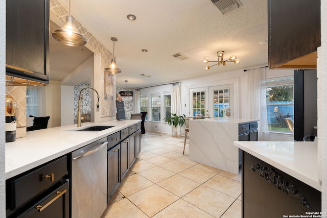 kitchen featuring a wealth of natural light, stainless steel dishwasher, hanging light fixtures, and sink