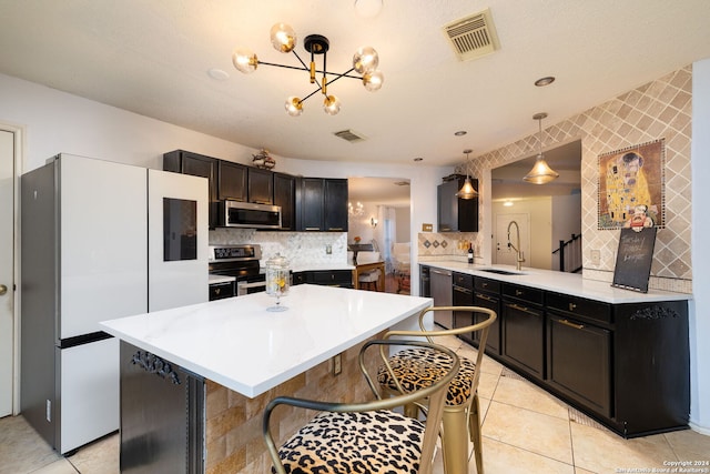 kitchen with kitchen peninsula, pendant lighting, a kitchen bar, decorative backsplash, and appliances with stainless steel finishes