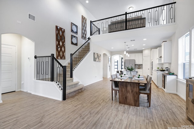 dining space featuring a towering ceiling and light hardwood / wood-style floors