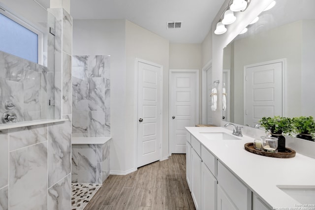 bathroom featuring vanity, wood-type flooring, and tiled shower