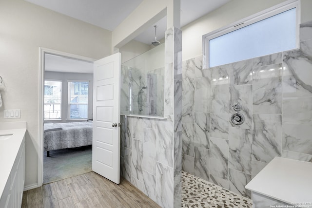 bathroom with hardwood / wood-style floors, tiled shower, and vanity