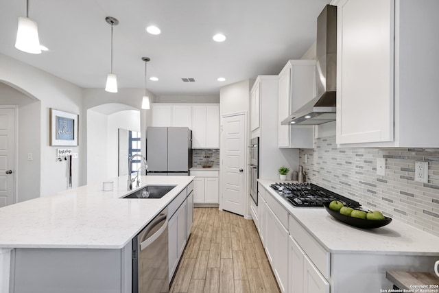 kitchen featuring appliances with stainless steel finishes, sink, wall chimney exhaust hood, and white cabinets