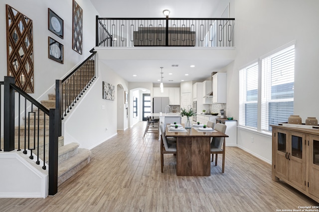 dining area with light hardwood / wood-style flooring and a high ceiling