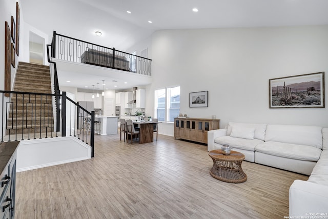 living room with high vaulted ceiling and light hardwood / wood-style flooring