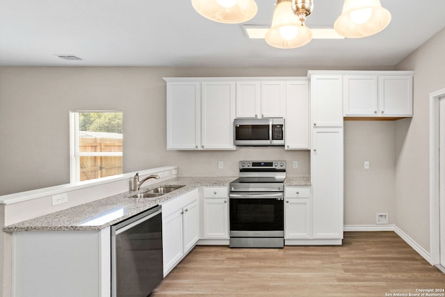 kitchen with white cabinetry, sink, appliances with stainless steel finishes, pendant lighting, and light wood-type flooring