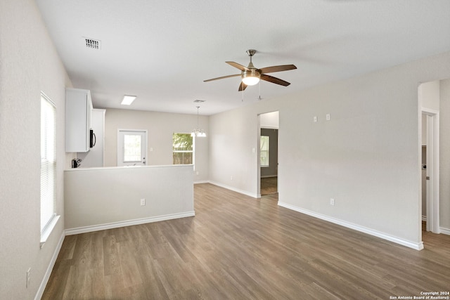 empty room with hardwood / wood-style floors and ceiling fan with notable chandelier