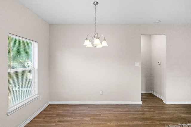 unfurnished room with a notable chandelier and dark hardwood / wood-style floors