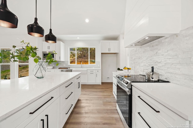 kitchen with white cabinets, decorative light fixtures, appliances with stainless steel finishes, and light hardwood / wood-style flooring