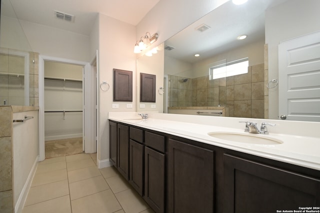 bathroom featuring vanity, tile patterned floors, and a tile shower