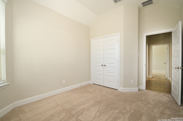 unfurnished bedroom with a closet, vaulted ceiling, and light carpet