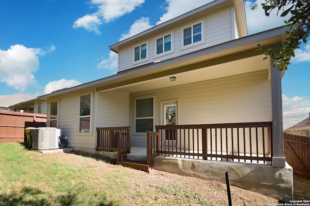 rear view of property featuring central air condition unit, a yard, and covered porch