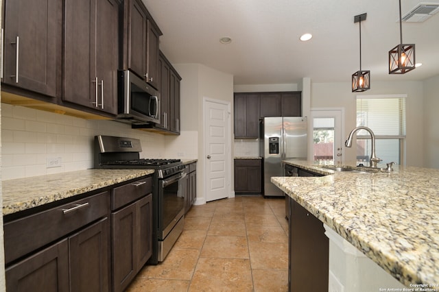 kitchen featuring stainless steel appliances, light stone counters, dark brown cabinetry, sink, and backsplash