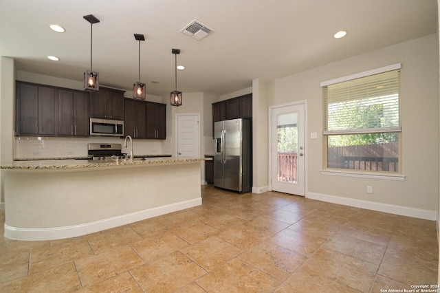 kitchen with stainless steel appliances, dark brown cabinetry, light stone counters, backsplash, and pendant lighting