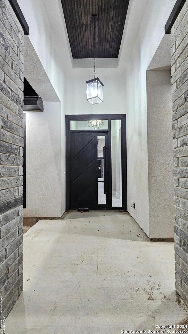 entryway with a tray ceiling, concrete floors, and a high ceiling