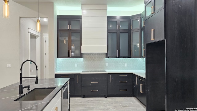 kitchen featuring sink, tasteful backsplash, dark stone countertops, pendant lighting, and light wood-type flooring