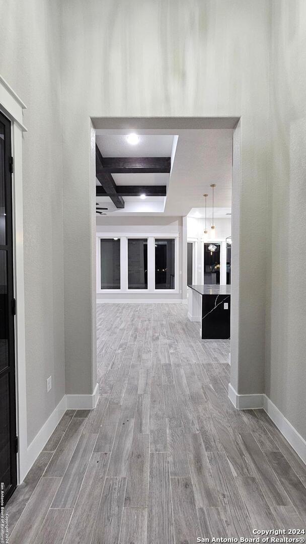 hall featuring hardwood / wood-style flooring, beam ceiling, and coffered ceiling