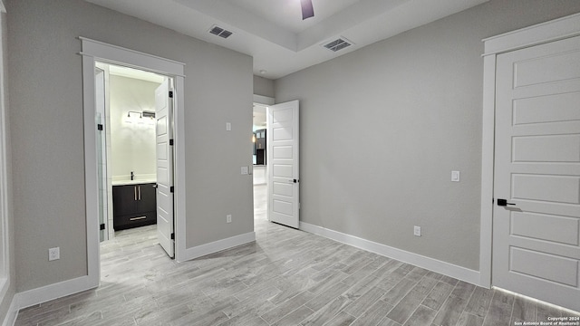 unfurnished bedroom with ensuite bathroom, ceiling fan, and light hardwood / wood-style floors