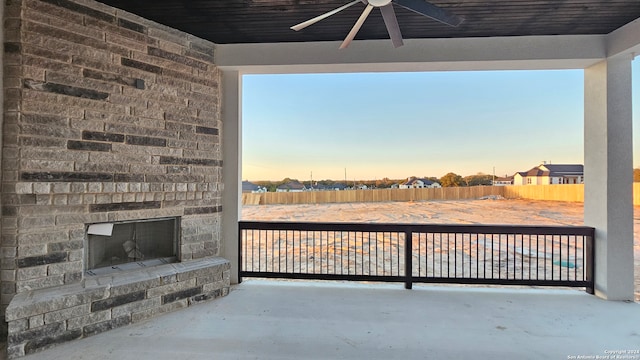 patio terrace at dusk with an outdoor brick fireplace and ceiling fan