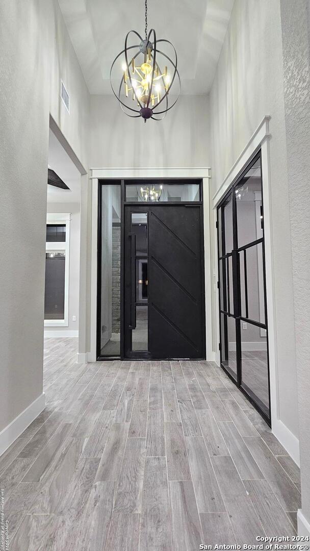 entrance foyer featuring a chandelier, light hardwood / wood-style floors, and a high ceiling