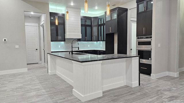 kitchen with pendant lighting, sink, decorative backsplash, light wood-type flooring, and double oven