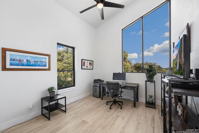 home office with ceiling fan, vaulted ceiling, and light hardwood / wood-style floors