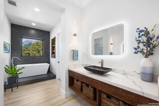 bathroom featuring wood-type flooring, vanity, and a bathtub