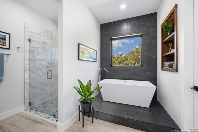 bathroom featuring hardwood / wood-style floors, plus walk in shower, and tile walls