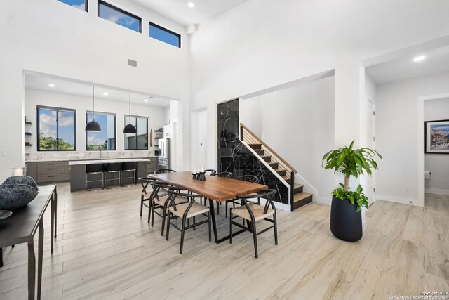 dining space featuring a towering ceiling and light hardwood / wood-style flooring