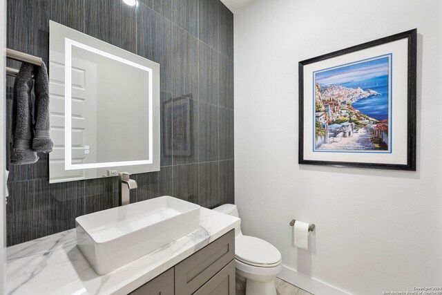 bathroom with tile walls, vanity, and toilet