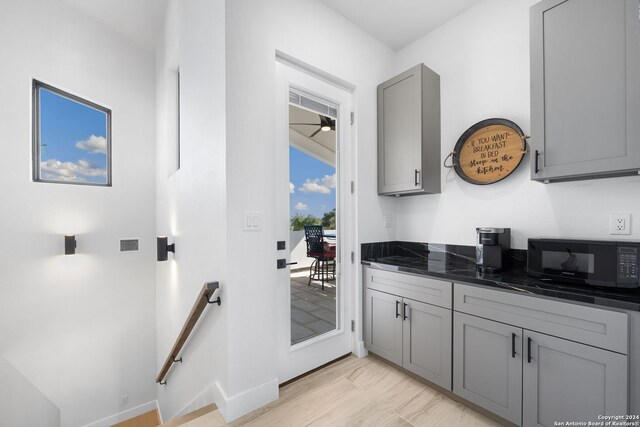 kitchen featuring gray cabinets, light wood-type flooring, and dark stone counters