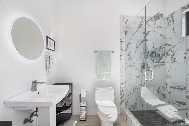 bathroom with hardwood / wood-style floors, sink, toilet, and a shower with shower door