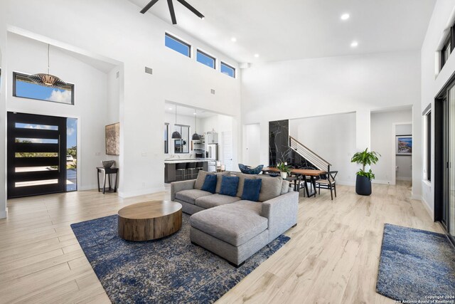 living room with high vaulted ceiling, ceiling fan, and light hardwood / wood-style floors